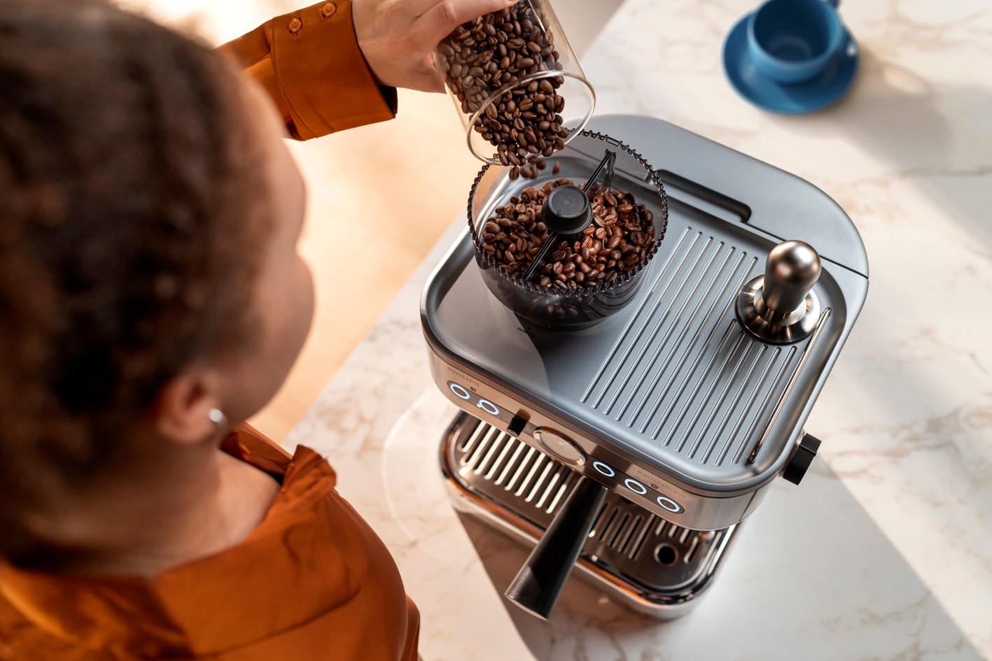 Jauna moteris pila kavos pupeles į „Philips Barista brew“ kavos pupelių talpyklą